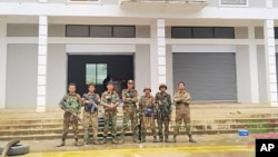 In this photo provided by Mandalay People's Defence, members of the Ta'ang National Liberation Army and Mandalay People's Defence Force pose for a photograph in front of a captured building in Nawnghkio township in Shan state, Myanmar, on June 26, 2024. 