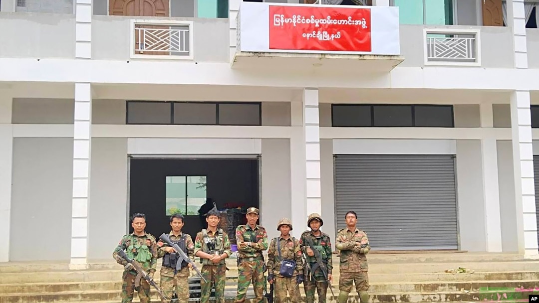 FILE - Members of the Ta'ang National Liberation Army and Mandalay People's Defense Force pose for a photograph in front of a captured building in Nawnghkio township, Shan state, June 26, 2024. (Mandalay People's Defense Force via AP)