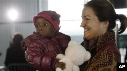 A French adoptive parent carries an orphan from Haiti at Roissy airport, outside of Paris, 22 Dec 2010