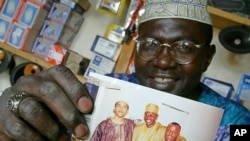 Dalam foto tertanggal 14/9/2004 ini, Malik Obama, saudara tiri presiden AS Barack Obama, memperlihatkan fotonya dengan Barack dan seorang temannya. Malik yang tinggal di Kenya, seorang Muslim,menjalankan poligami yang legal dilakukan di Kenya. 