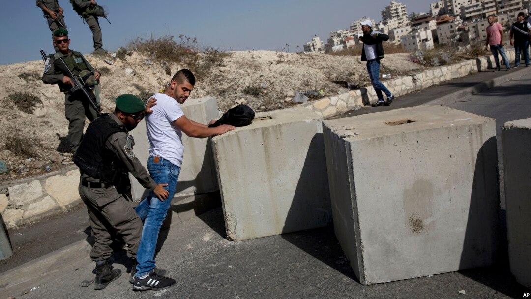 FILE - Israeli border police search a Palestinian next to newly placed concrete blocks in an East Jerusalem neighborhood, Oct. 15, 2015.