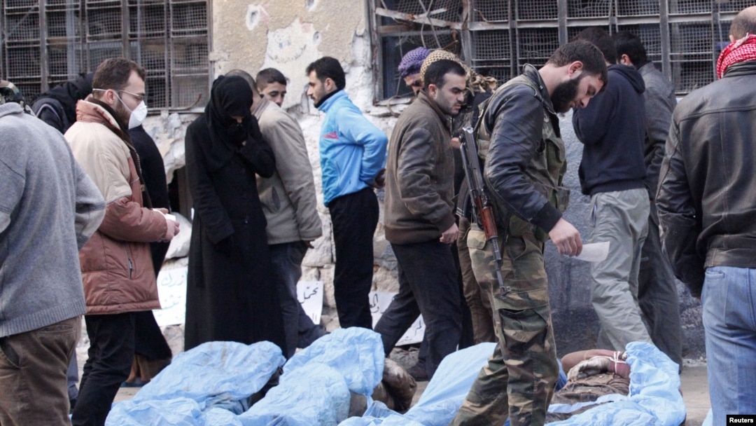 Free Syrian Army fighters and residents attempt to identify bodies found along a river, at a school used as a field hospital in Aleppo, Syria, January 29, 2013