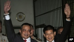 Red Shirt leaders Jatuporn Prompan, left, and Nisit Sinthuprai, raise their hands behind bars at the Criminal Court in Bangkok, May 12, 2011 as they are taken to the prison after their bails were revoked.