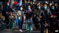 Commuters wearing face masks to protect against the coronavirus ride bicycles across an intersection in Beijing, Thursday, Oct. 22, 2020. The number of confirmed COVID-19 cases across the planet has surpassed 40 million, but experts say that is only the t