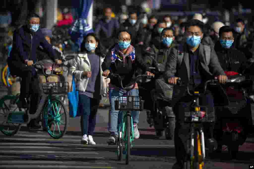 Commuters wearing face masks to protect against the coronavirus ride bicycles across an intersection in Beijing, Thursday, Oct. 22, 2020. The number of confirmed COVID-19 cases across the planet has surpassed 40 million, but experts say that is only the t
