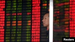 An investor stands in front of an electronic board showing stock information at a brokerage house in Shanghai, China, Sept. 2, 2015. 