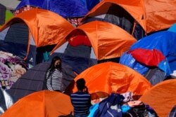 FILE - Tents used by migrants seeking asylum in the United States line an entrance to the border crossing, in Tijuana, Mexico, March 1, 2021.