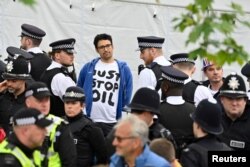 Manifestantes del grupo "Just Stop Oil" son detenidos por agentes de policía en la multitud cerca de la Abadía de Westminster en el centro de Londres el 6 de mayo de 2023. JUSTIN TALLIS/vía REUTERS