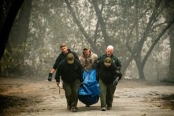 FILE - Sheriff's deputies recover the remains of a victim of the Camp Fire in Paradise, Calif., Nov. 10, 2018.