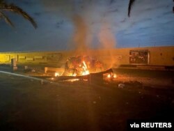 FILE - Burning debris is seen on a road near Baghdad International Airport following a U.S. airstrike that killed Iranian general Qassem Soleimani and others, Jan. 3, 2020, in this image obtained via social media.