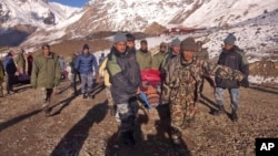 In this photo provided by the Nepalese army, soldiers carry an avalanche victim to an airlift transfer point in Thorong La pass area, Nepal, Oct. 15, 2014.