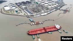 FILE - Tugboats aid a crude oil tanker at an oil terminal in Zhoushan, Zhejiang province, China. July 18, 2022.