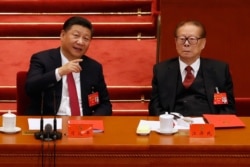 FILE - Chinese President Xi Jinping, left, chats with former President Jiang Zemin during the closing ceremony for the 19th Party Congress at the Great Hall of the People in Beijing, Oct. 24, 2017.