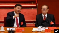 FILE - Chinese President Xi Jinping, left, chats with former President Jiang Zemin during the closing ceremony for the 19th Party Congress at the Great Hall of the People in Beijing, Oct. 24, 2017.