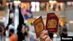 A pro-democracy demonstrator holds British National Overseas (BNO) passports during a protest against new national security legislation in Hong Kong, China June 1, 2020. REUTERS/Tyrone Siu