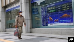 A man walks past an electronic stock indicator of a securities firm in Tokyo, Wednesday, Jan. 6, 2016. 