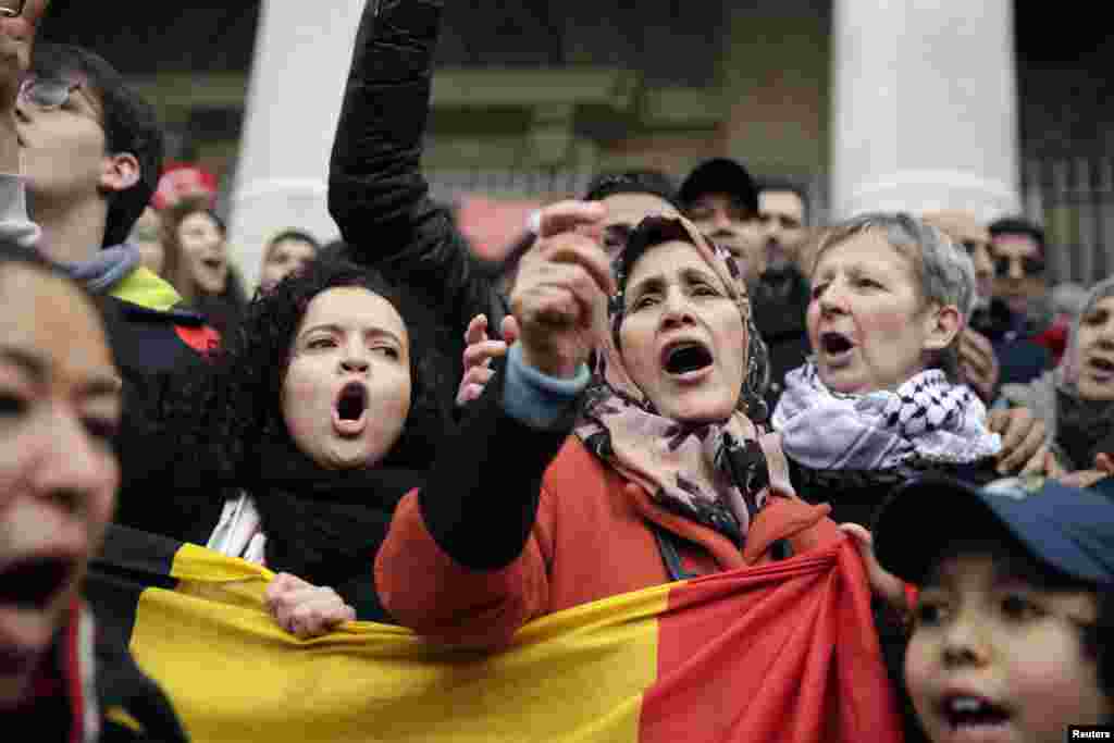 Warga bernyanyi saat berkumpul di sebuah memorial di Place de la Bourse (Beursplein) di Brussels (23/3), sehari setelah serangan bom yang mengguncang ibukota. (AFP/Kenzo Tribouillard)