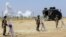 Turkish soldiers stand guard near the Mursitpinar border gate in Sanliurfa province as smoke rises in the Syrian town of Kobani in the background, June 27, 2015.