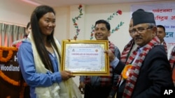 Nepalese woman climber Lhakpa Sherpa, left, is honored with an honorary certificate in Kathmandu, Nepal, Wednesday, May 23, 2018. (AP Photo/Niranjan Shrestha)