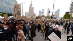 Women's rights activists with posters of the Women's Strike action protest in Warsaw, Poland, Oct. 28, 2020 against recent tightening of Poland's restrictive abortion law.