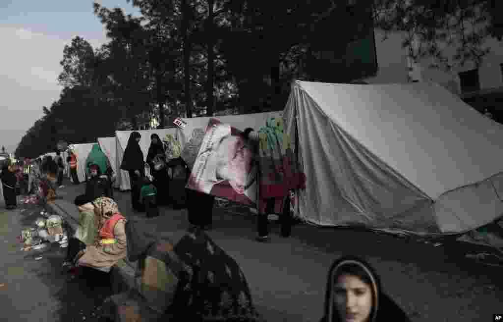 A supporter of cleric Tahir-ul-Qadri enters her tent carrying an image of him, while she and others camp near the parliament, during an anti-government rally in Islamabad, Pakistan, January 16, 2013.