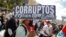 Un hombre sostiene una pancarta que dice "Corruptos" durante una protesta contra las acciones del Gobierno del presidente de El Salvador, Nayib Bukele, como el uso de bitcoin y reformas legales para extender su mandato, en San Salvador, El Salvador, el 12 de diciembre de 2021.