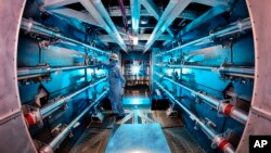 In this 2012 image provided by Lawrence Livermore National Laboratory, a technician reviews an optic inside the preamplifier support structure at the Lawrence Livermore National Laboratory in Livermore, California. 