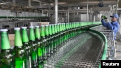 중국 산둥성 일자오시의 칭따오 맥주 공장 조립 라인에서 한 직원이 맥주병을 점검하고 있다. (자료사진)