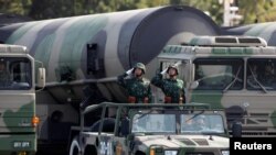 Soldados del ejército chino saludan frente a misiles con capacidad nuclear durante un desfile en Beijing el 1 de octubre de 2009.