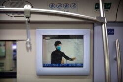 A public service announcement that encouraging people to wear face masks plays on a subway train during the morning rush hour in Beijing, Feb. 3, 2020.