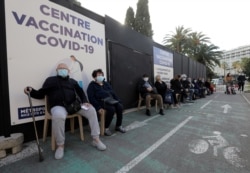 Senior citizens, wearing protective face masks, wait at a coronavirus vaccination center in Nice, France, Jan. 25, 2021.