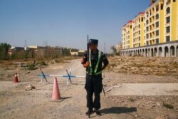 FILE - A Chinese police officer takes his position by the road near what is officially called a vocational education center in Yining in Xinjiang Uighur Autonomous Region, China, Sept. 4, 2018.