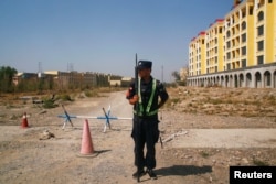 FILE - A Chinese police officer takes his position by the road near what is officially called a vocational education center in Yining in Xinjiang Uighur Autonomous Region, China, Sept. 4, 2018.
