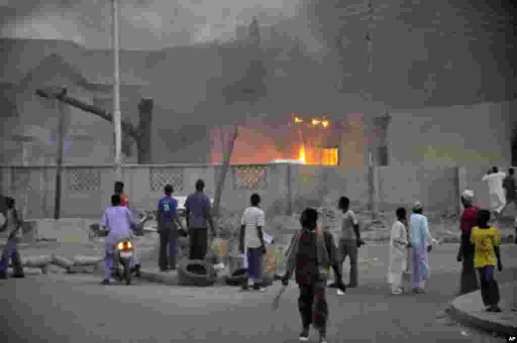 People watch as smoke rises from the police headquarters after it was hit by a blast in Nigeria's northern city of Kano January 20, 2012.