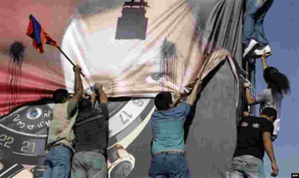 Lebanese of Armenian descent carry an Armenian flag as they tear up a poster showing Turkish Prime Minister Recep Tayyip Erdogan during a protest against his visit, in Beirut's Martyrs' Square, Lebanon, Thursday, Nov. 25, 2010. Armenians accuse Turkey of