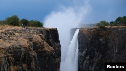 FILE - Visitors walk along a walkway as spray rises up from a flowing section of Victoria Falls, Zimbabwe, Dec. 4, 2019. 