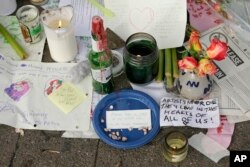 Candles burn and notes are left at a makeshift memorial near the site of a warehouse fire Wednesday.