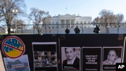 Letreros y fotografías de personas asesinadas, incluido el periodista Brent Renaud, cuelgan de una cerca durante una protesta contra la invasión rusa de Ucrania en el Parque Lafayette cerca de la Casa Blanca, el 13 de marzo de 2022, en Washington. 