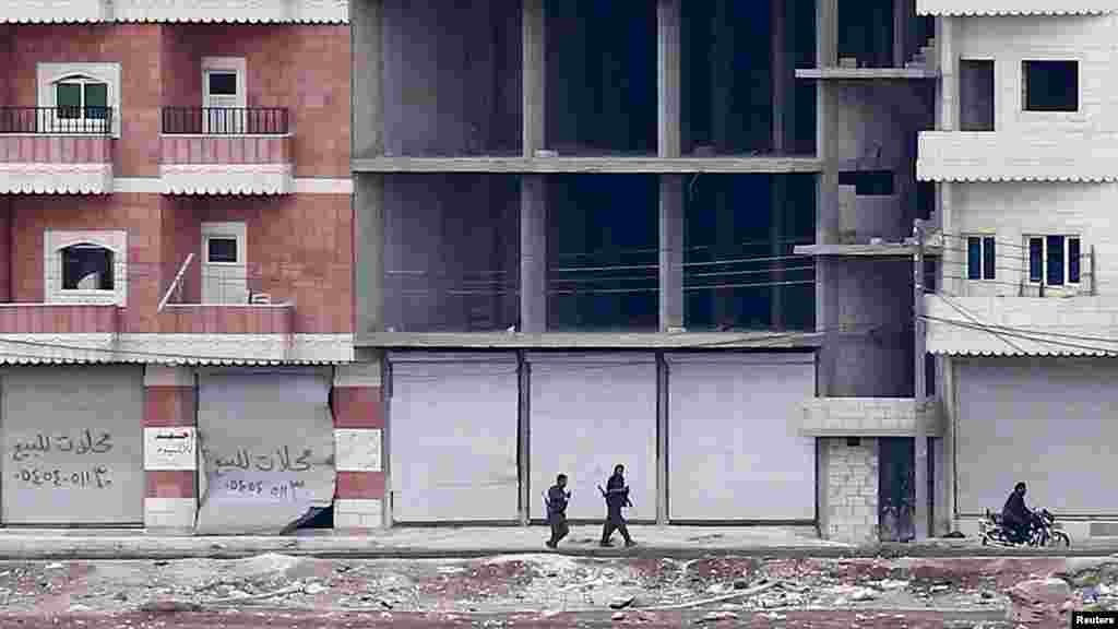 Kurdish fighters walk through a street in the Syrian town of Kobani, Oct. 19, 2014. 