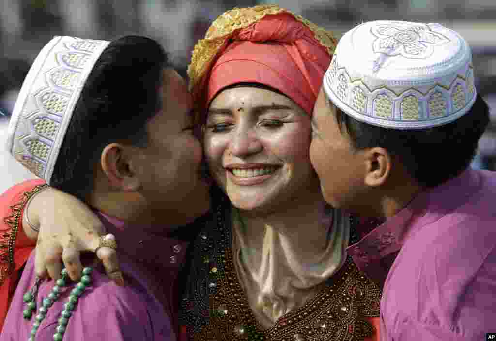 Dua anak laki-laki Filipina mencium ibunya saat berfoto bersama setelah melaksanakan salat Ied untuk merayakan Idulfitri di Manila, Filipina, Rabu, 5 Juni 2019. (Foto: Aaron Favila/AP)