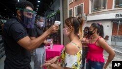 10일 브라질 상파울루의 쇼핑 거리에서 마스크를 착용한 시민들이 상점으로 들어가기 전 체온을 측정을 받고 있다. 