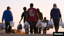 Un grupo de inmigrantes agrícolas regresan a su campamento en las afueras de San Diego, California.