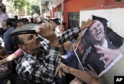 Un manifestant frappant un portrait du président syrien à l'aide sa chaussure devant l'ambassade de Syrie au Caire