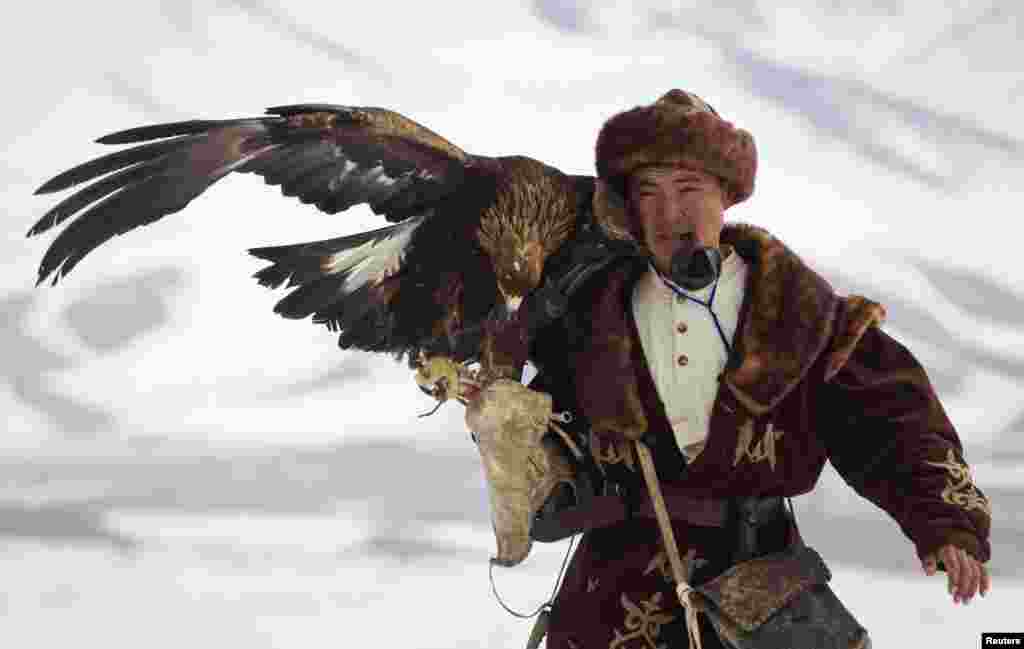 A Kazakh hunter walks with his tamed golden eagle during an annual hunting competition in Chengelsy Gorge, some 150 km (93 miles) east of Almaty, Kazakhstan, Feb. 22, 2013. 