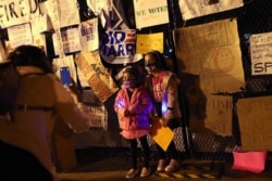 A woman poses her daughters at the wall fencing off the White House under a sign they made that says "daughter of immigrants" after Joe Biden was declared winner of the 2020 U.S. presidential election, at BLM Plaza in Washington, Nov. 7, 2020.