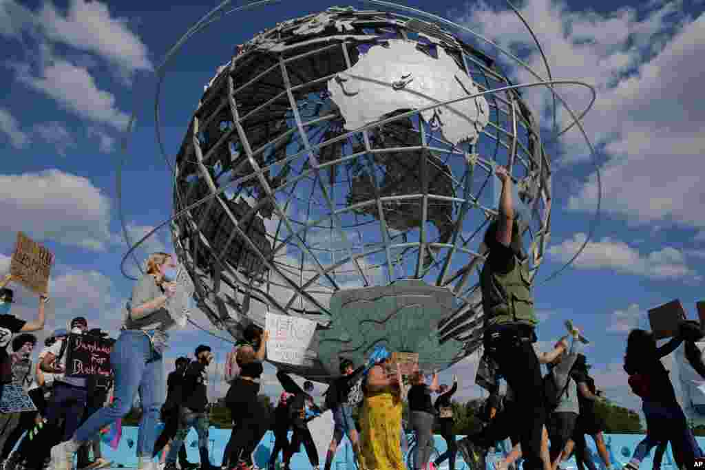 Protesters march around a large sculpture of a globe in Flushing Meadows Corona Park in the Queens borough of New York, May 31, 2020.