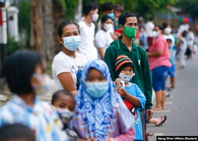 Orang-orang yang mengenakan masker pelindung antre untuk menerima makan gratis berbuka puasa selama bulan suci Ramadhan di tengah pandemi COVID-19 di Jakarta, 15 April 2021. (Foto: REUTERS/Ajeng Dinar Ulfiana)