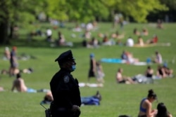 Seorang Polisi Kota New York (NYPD) mengenakan masker saat menjaga keamanan di sekitar Sheep Meadow, Central Park di tengah pandemi COVID-19 di Manhattan, New York, AS, 15 Mei 2020.
