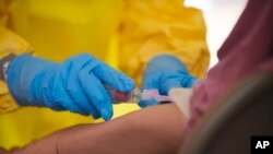 美國疾病於預防控制中心人員指導醫護人員如何替伊波拉病人注射疫苗。