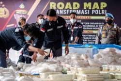 Polisi mengatur barang bukti narkoba saat berlangsungnya konferensi pers di Mabes Polri, setelah petugas berhasil mengamankan 2,5 ton sabu dari jaringan Timur Tengah, Malaysia, dan Indonesia, di Jakarta, 28 April 2021. (Antara Foto / M Risyal Hidayat / via REUTERS)